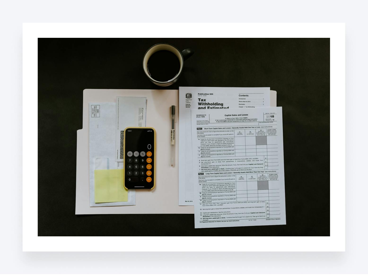 A tax return form, an envelope, a pen and a calculator app