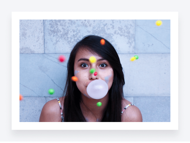 Young woman blows a bubble with classic pink bubble gum.